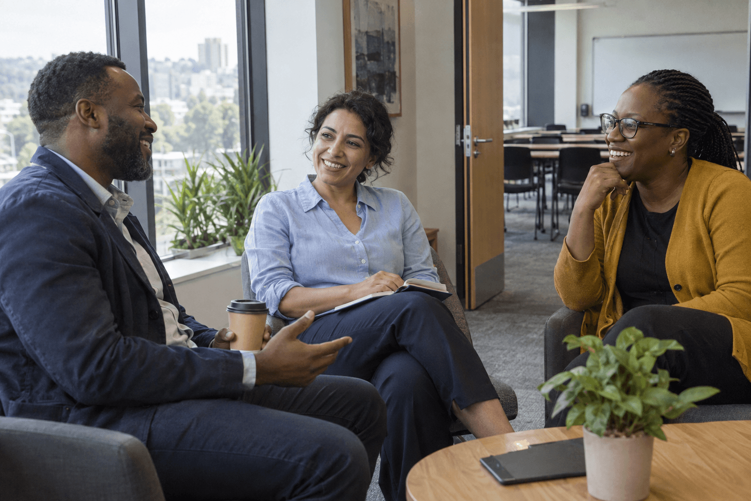 Scène d’illustration : trois professionnels discutent pendant une pause, près d’une salle de formation.